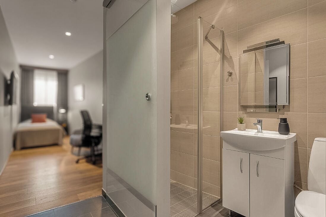 Ein modernes Badezimmer mit einer Duschkabine aus Glas, einem weißen Waschbecken und einem Spiegel darüber.