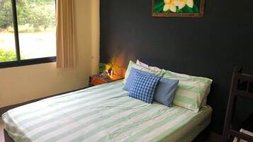 A bed with striped bedding, a nightstand with a lamp, and a painting of flowers on the wall.