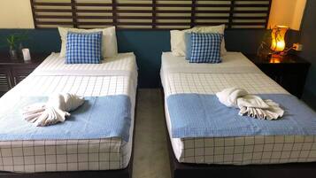 Two twin beds with blue and white checkered bedding, a wooden headboard, and a bedside lamp.