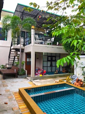 A residential property with a swimming pool, a staircase, and a covered outdoor area.
