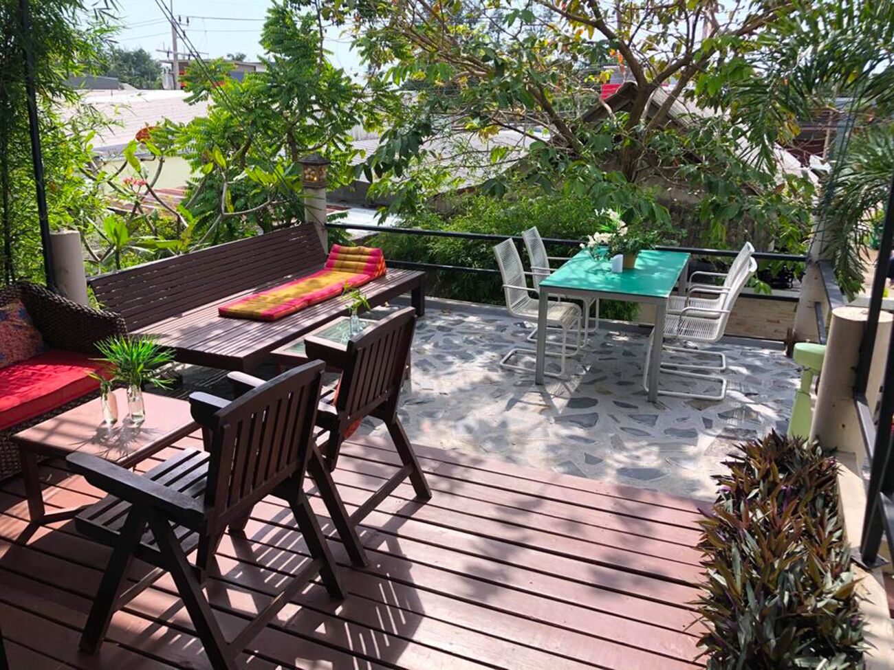 Une terrasse extérieure aménagée avec du mobilier en bois, notamment une table et des chaises, entourée de verdure et offrant une vue sur le paysage urbain.