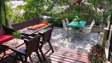 Une terrasse extérieure aménagée avec du mobilier en bois, notamment une table et des chaises, entourée de verdure et offrant une vue sur le paysage urbain.