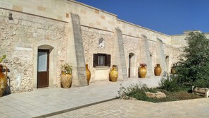 A historic building with arched doorways and large vases placed outside. - Agriturismo Masseria Nuova (Francavilla Fontana)