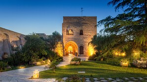 A stone building with a central archway, surrounded by a well-maintained garden and a stone pathway.