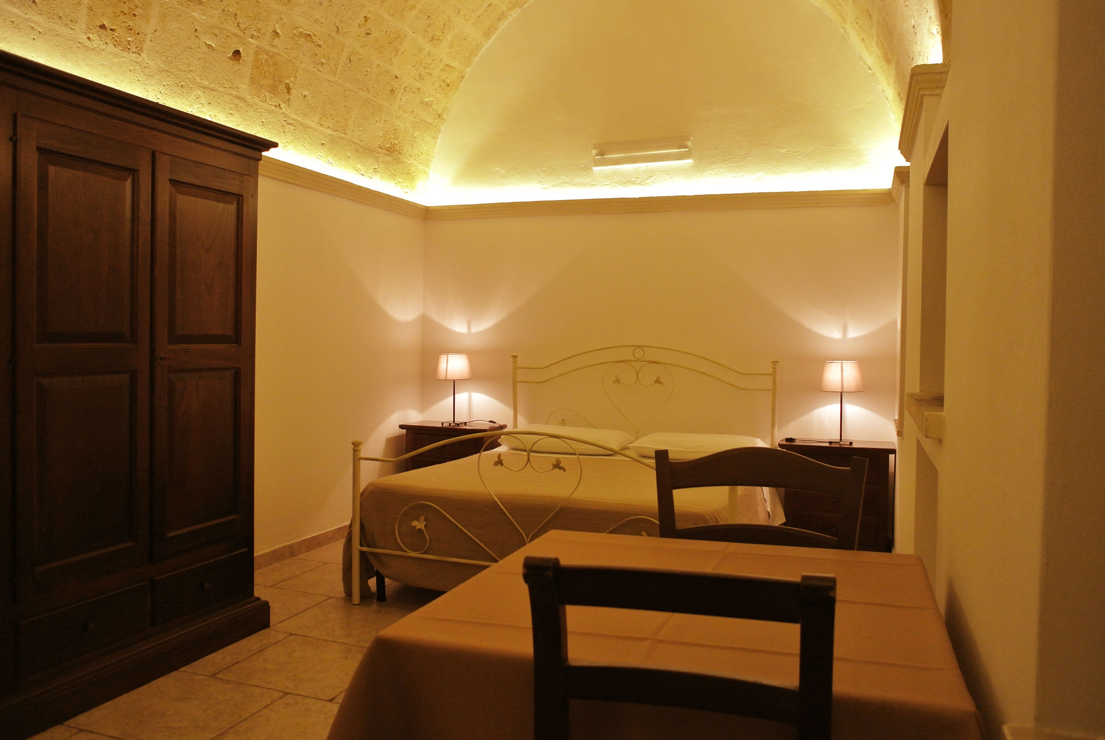 A bedroom with a bed, bedside tables, a chair, and a wardrobe.