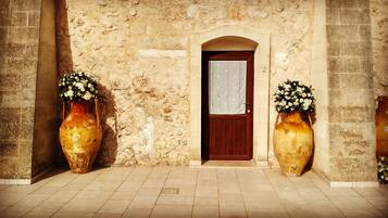 A stone building with a wooden door and two large vases with flowers.