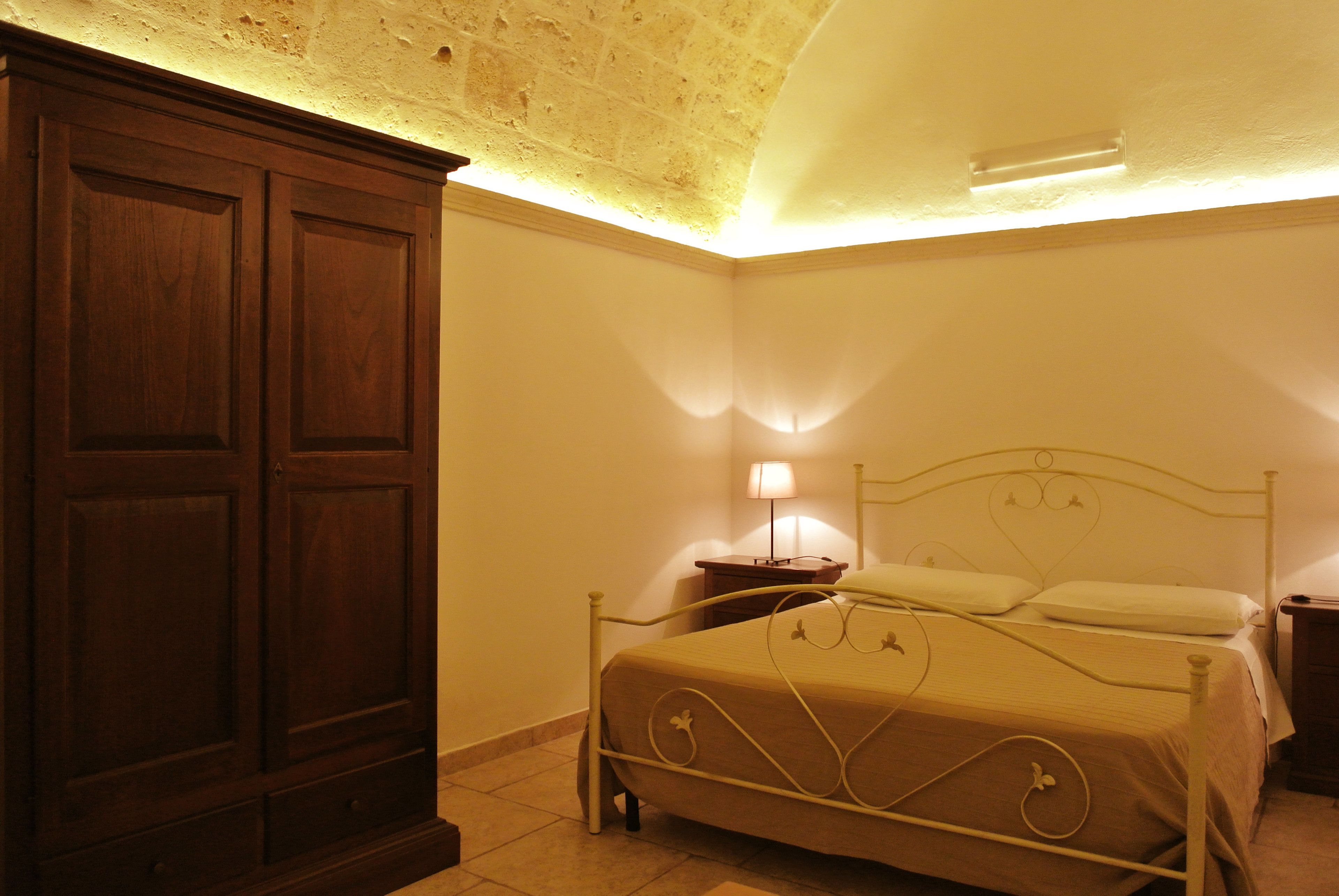 Une chambre à coucher avec un lit, une armoire en bois et une table de chevet avec une lampe.