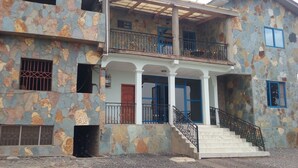 Edifici de dues plantes amb façana de pedra, un balcó i una escala que condueix a l'entrada.