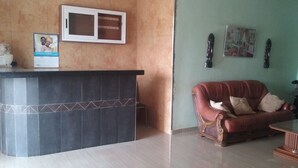 Una zona de recepció amb un taulell de terres negres, un sofà de cuir vermell i un quadre al mur.