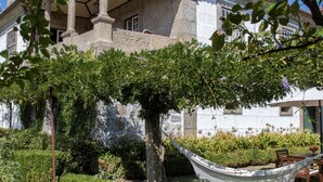 A house with a covered patio, a hammock, and a well-maintained garden. - Casa do Ribeiro (Guimarães)