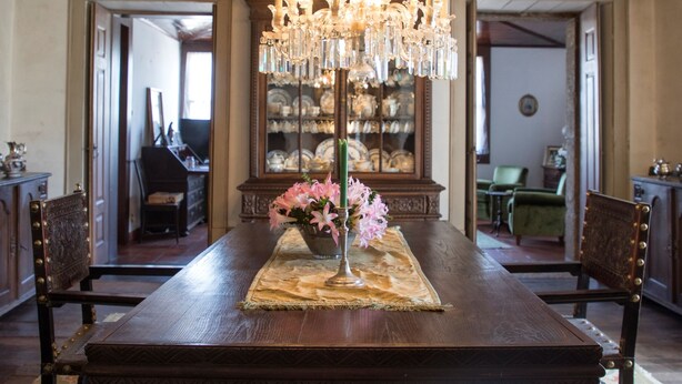 A dining room with a large wooden table, ornate chandelier, and patterned carpet. - Casa do Ribeiro (Guimarães)