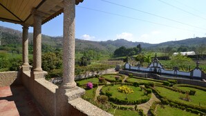 A garden with a fountain, a white building with ornate architecture, and a view of the surrounding countryside. - Casa do Ribeiro (Guimarães)