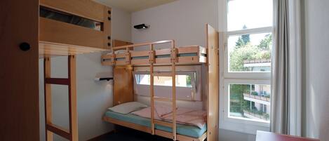 A bunk bed room with a window, a desk, and a door.