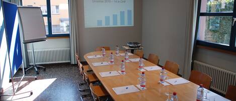 A conference room with a long table, chairs, water bottles, and a presentation screen displaying a graph.