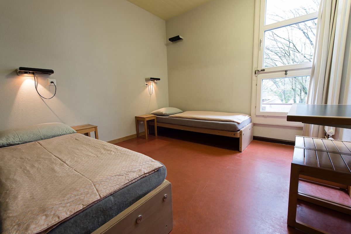 Un dormitorio con una cama, un escritorio y una ventana.