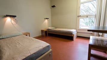 Un dormitorio con una cama, un escritorio y una ventana.