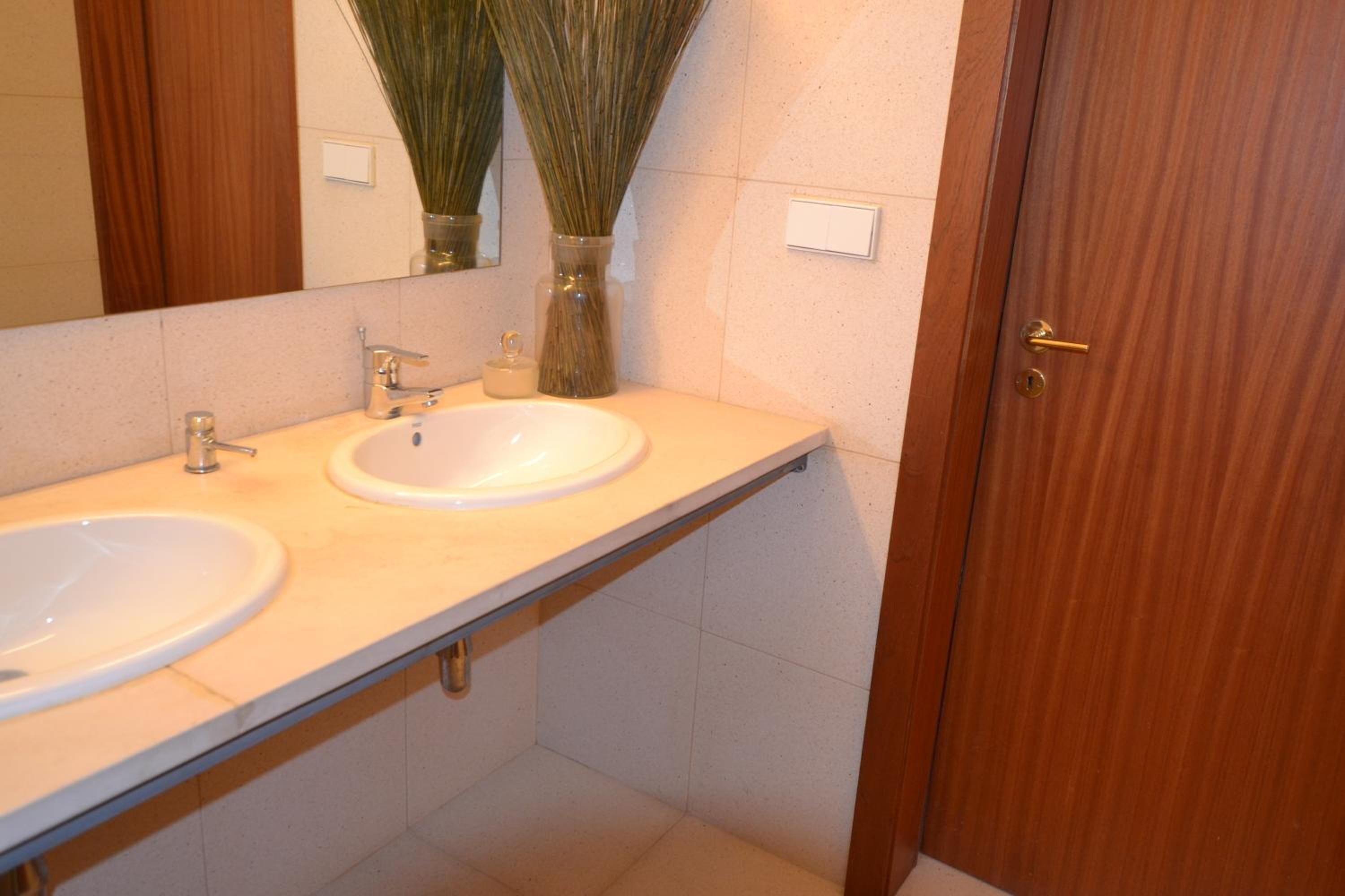 Un baño con dos lavamanos, un espejo y una puerta de madera.