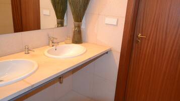 Un baño con dos lavamanos, un espejo y una puerta de madera.