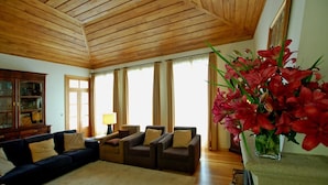 Ein Wohnzimmer mit Holzboden, einem dunkelblauen Sofa, einem braunen Sofa, einem kleinen Tisch mit einer Lampe und einem Blumenstrauß in Rot.
