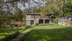 Ein Haus aus Stein mit rotem Ziegeldach, einer Steintreppe und einem gepflegten Rasen.