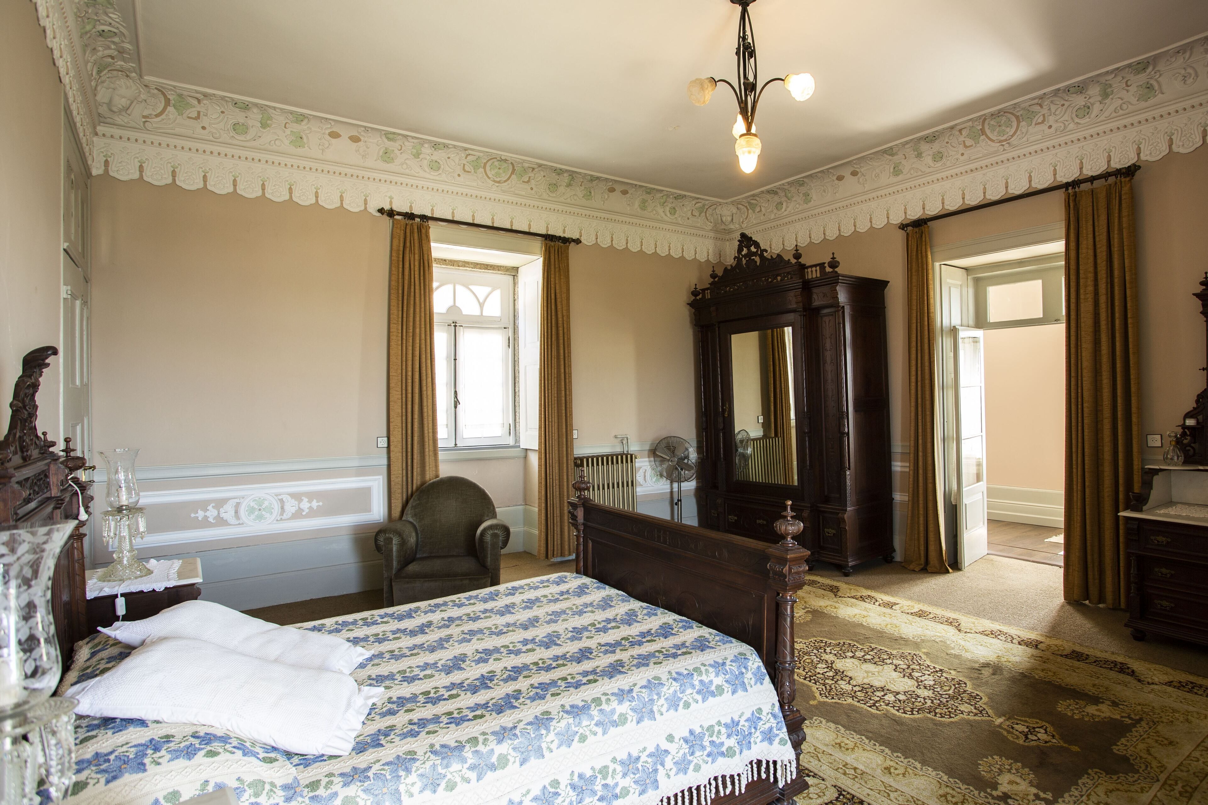 Un dormitorio con una cama grande, un aparador de madera, un espejo y una silla.