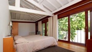 Ein Schlafzimmer mit einem großen Bett, einem Fernseher und einem Fenster mit Vorhängen.