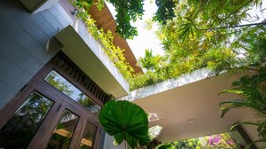 A modern building with a glass facade, a rooftop garden, and lush greenery. - Hanging Garden Hoi An (Da Nang)