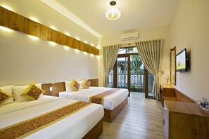 A hotel room with two beds, wooden headboards, a wooden desk, and a large window with curtains. - Hanging Garden Hoi An (Da Nang)
