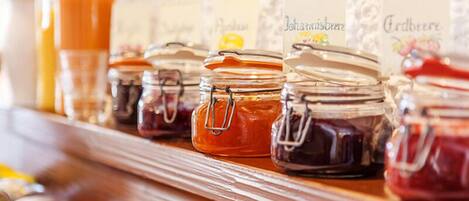 A row of glass jars with metal clasps, each labeled with a name, likely containing different types of preserves or jams.