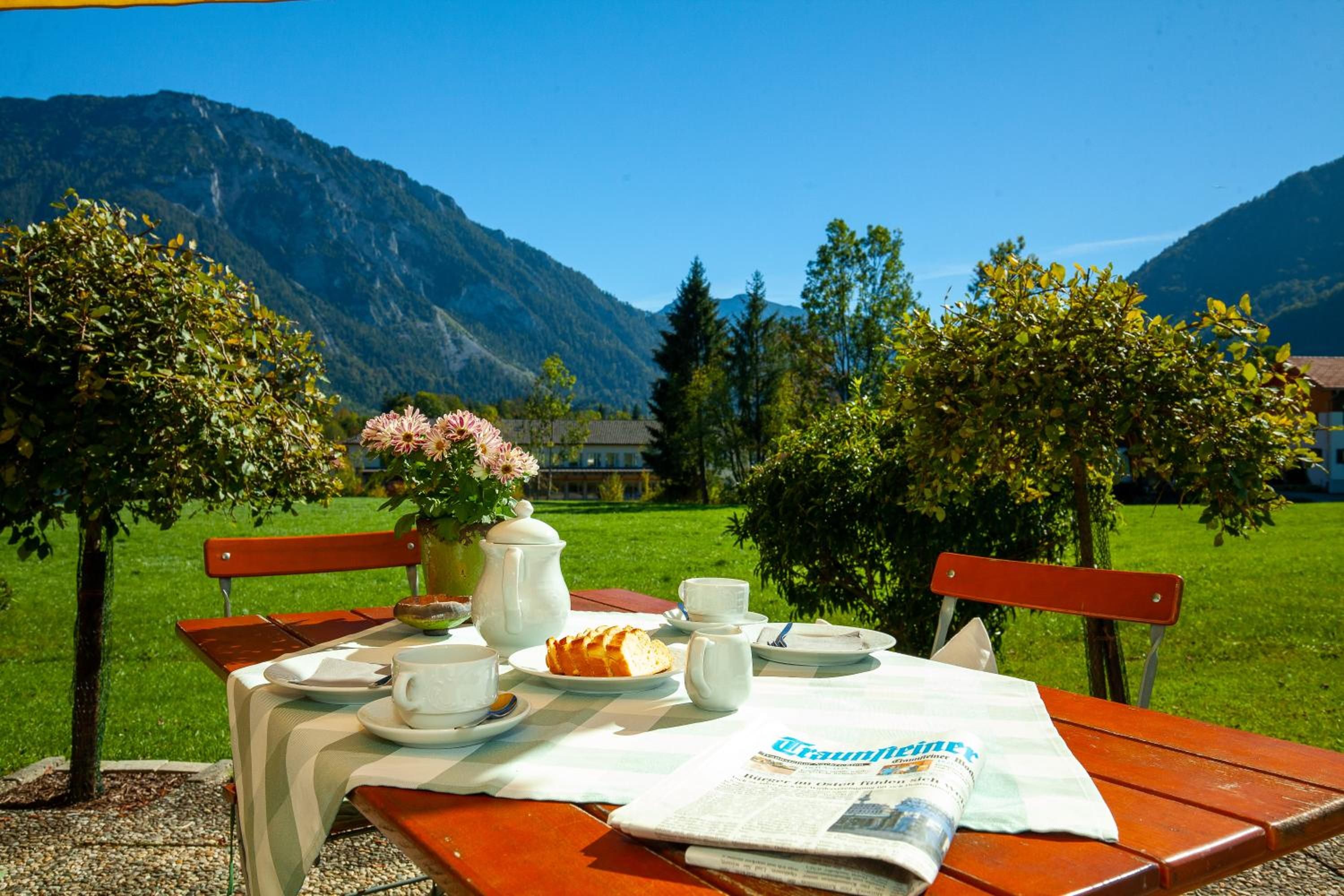 A picnic setup with a table, benches, a newspaper, and a view of mountains.