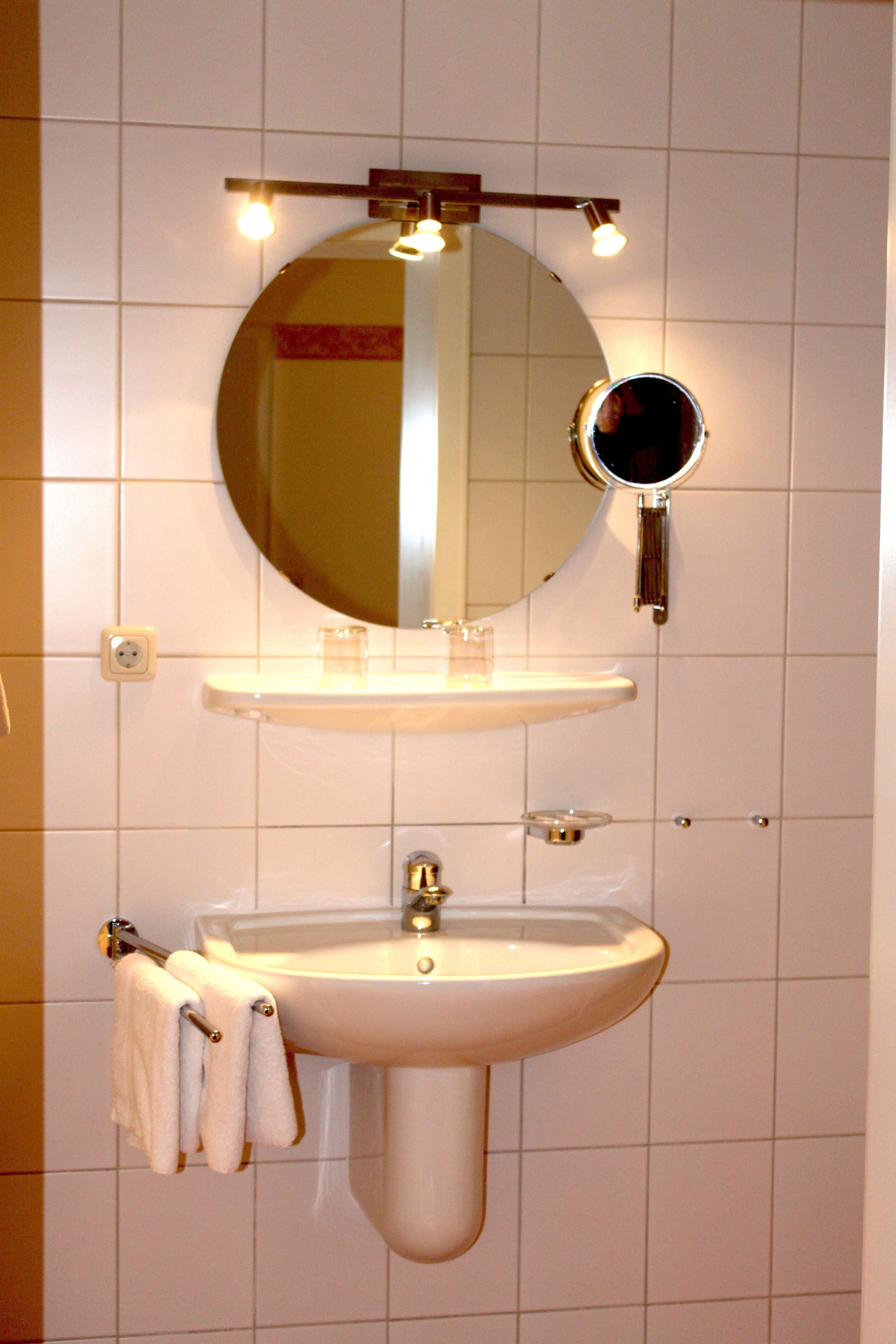 A bathroom with a white sink, a mirror, and a towel rack.
