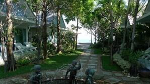 Un jardín con fuente, sillas de descanso y un sendero que lleva a un edificio.