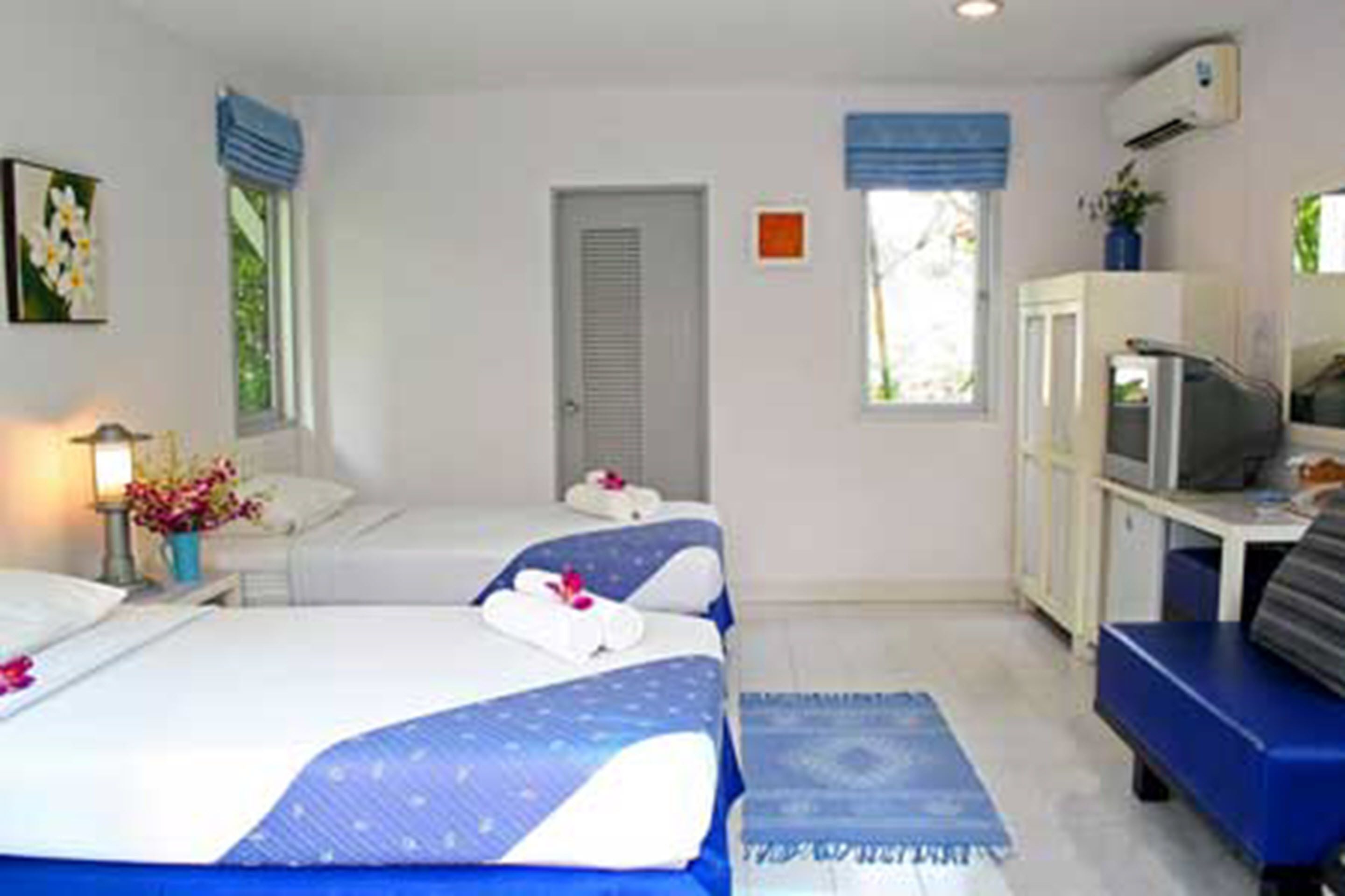 A hotel room with two beds, a desk with a computer, and a TV.