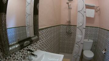 Baño con lavamanos, inodoro, ducha y espejo.