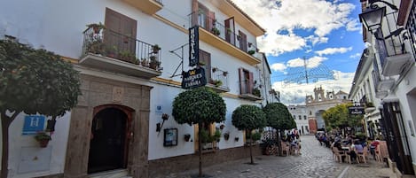 A cobblestone street with a hotel named "Hostal Marques de Zahara" and a sign for "Cerveceria el Gallo".