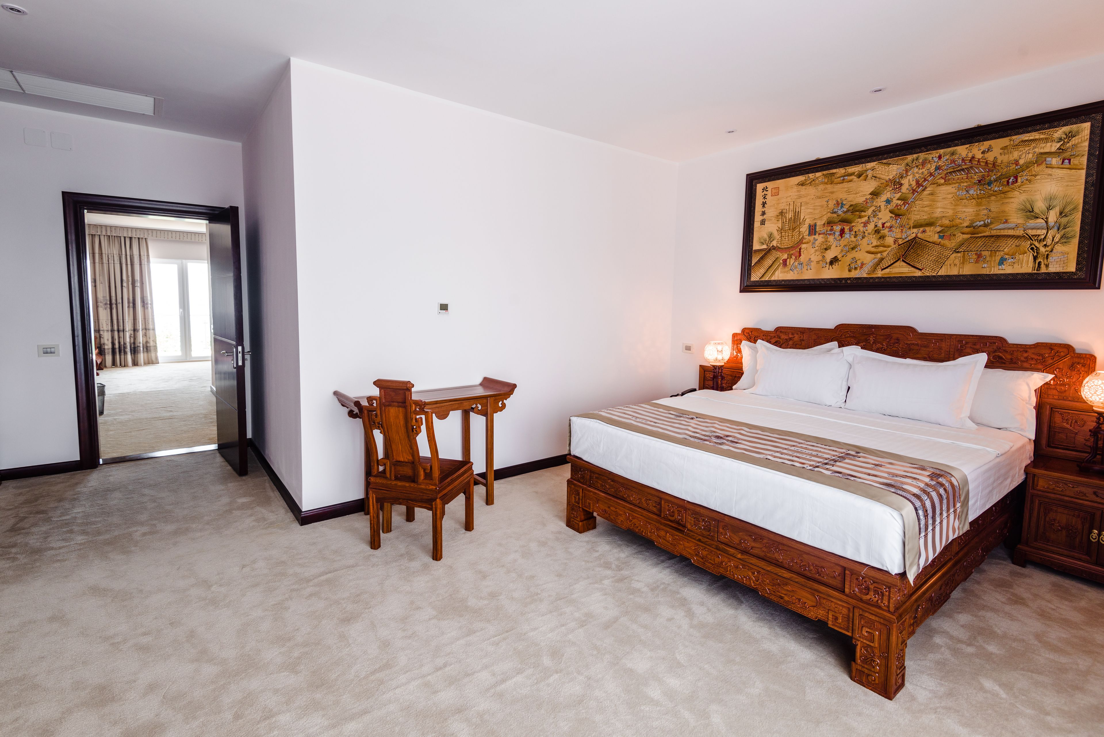 Un dormitorio con una cama grande, un escritorio de madera y un cuadro tradicional en la pared.