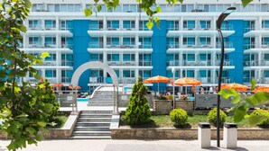 A modern hotel with a blue and white facade, outdoor seating with orange umbrellas, and a central staircase leading to the entrance. - Hotel Bavaria Blu (Constanta)