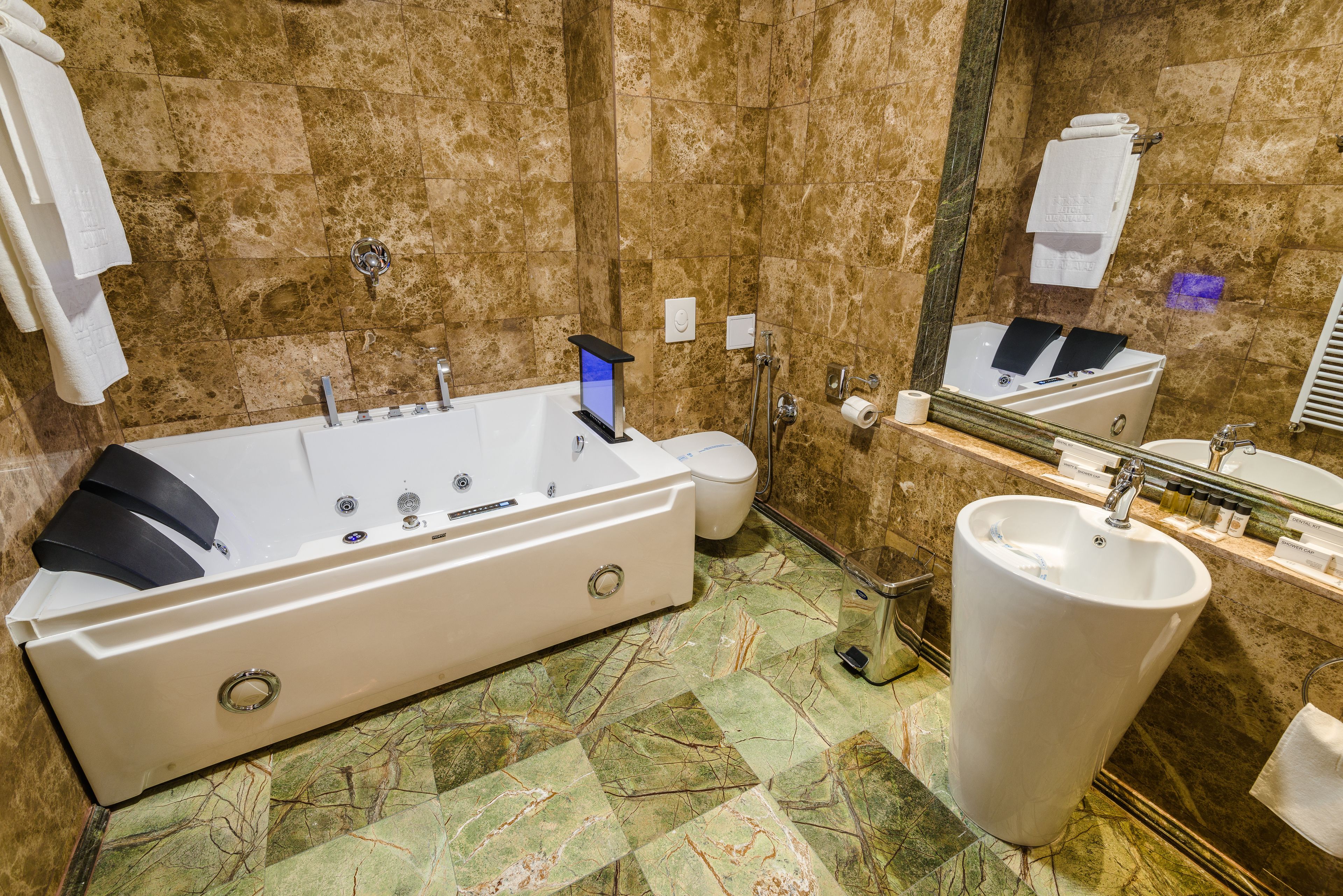 A bathroom with a large bathtub, a toilet, a sink, and a mirror.