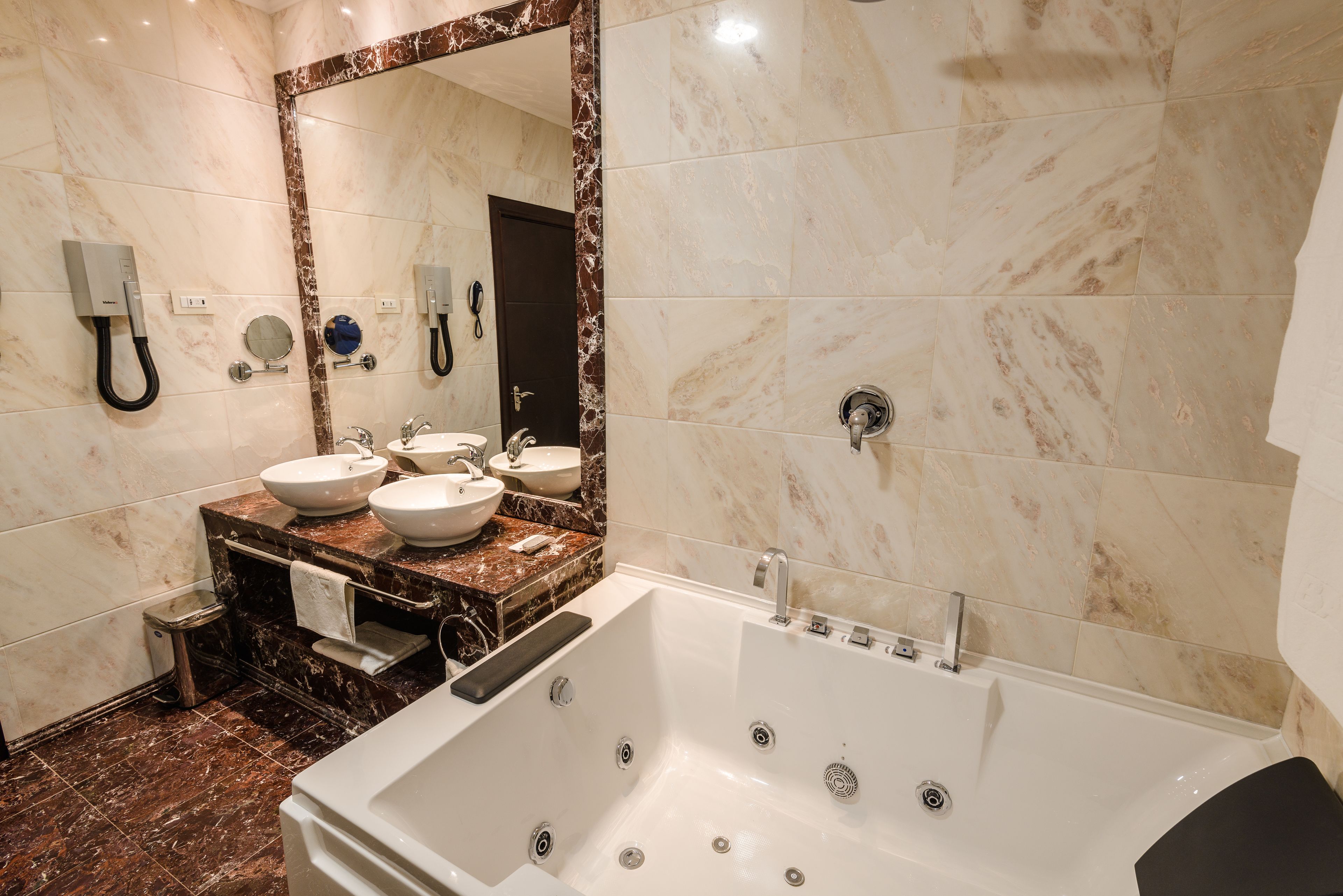 Un baño moderno con una bañera grande, dos lavamanos, un tocador con encimeras de mármol y un espejo amplio.