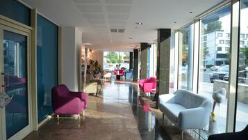 Un hall de hotel con un muro de cristal, una recepción y zonas de estar.