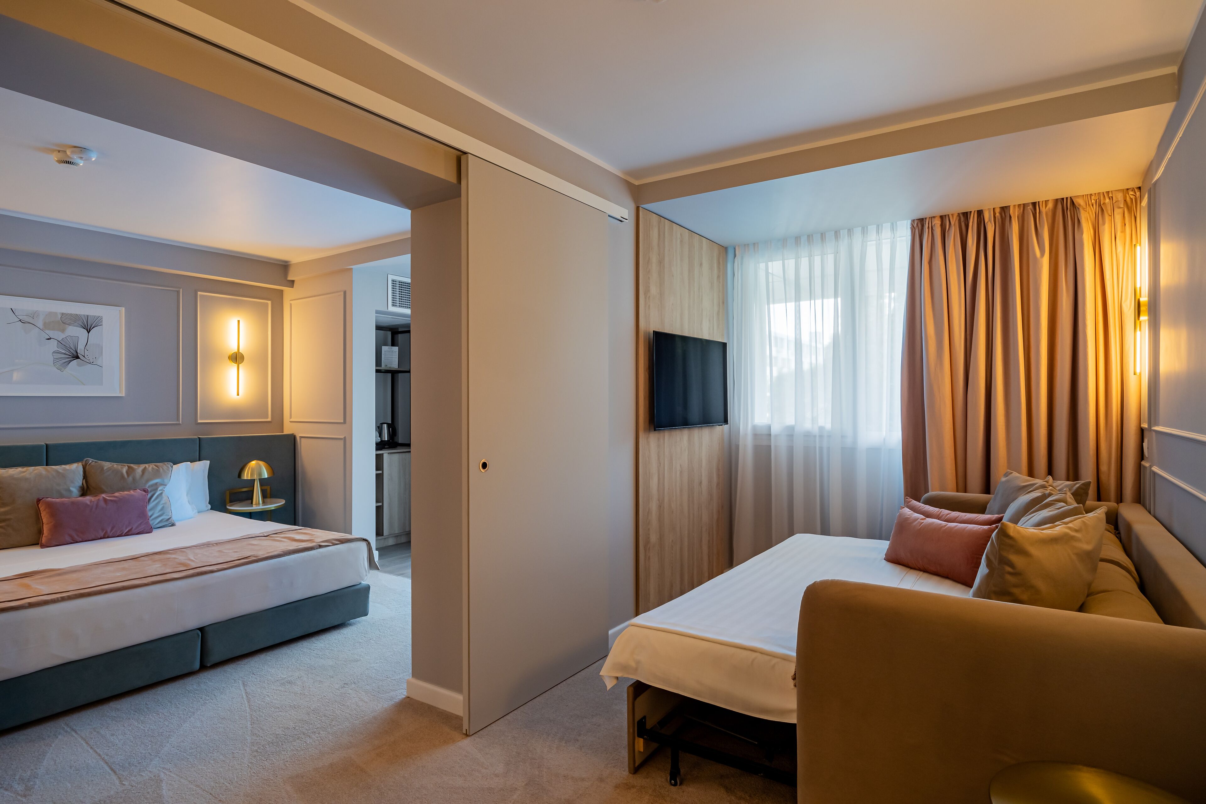 Une chambre d’hôtel avec un lit, un canapé, une télévision et un tableau au mur.