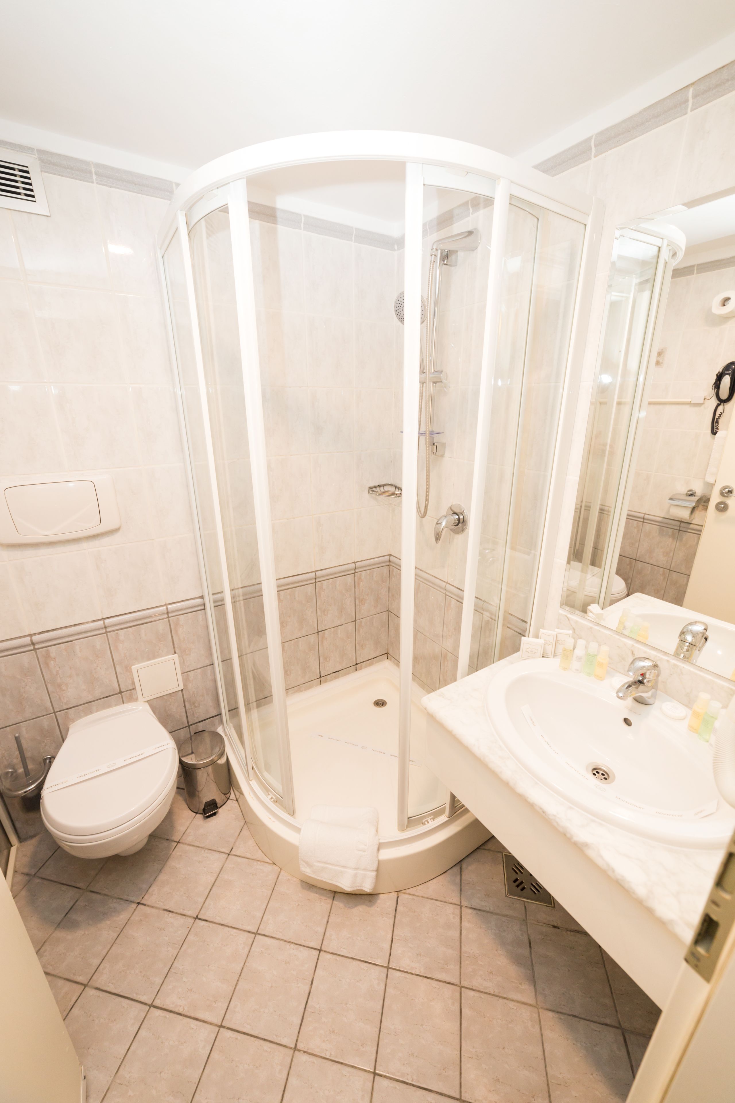 A modern bathroom with a glass-enclosed shower, a white sink, and a toilet.