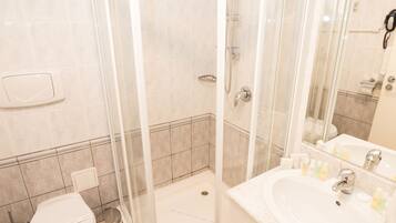 A modern bathroom with a glass-enclosed shower, a white sink, and a toilet.