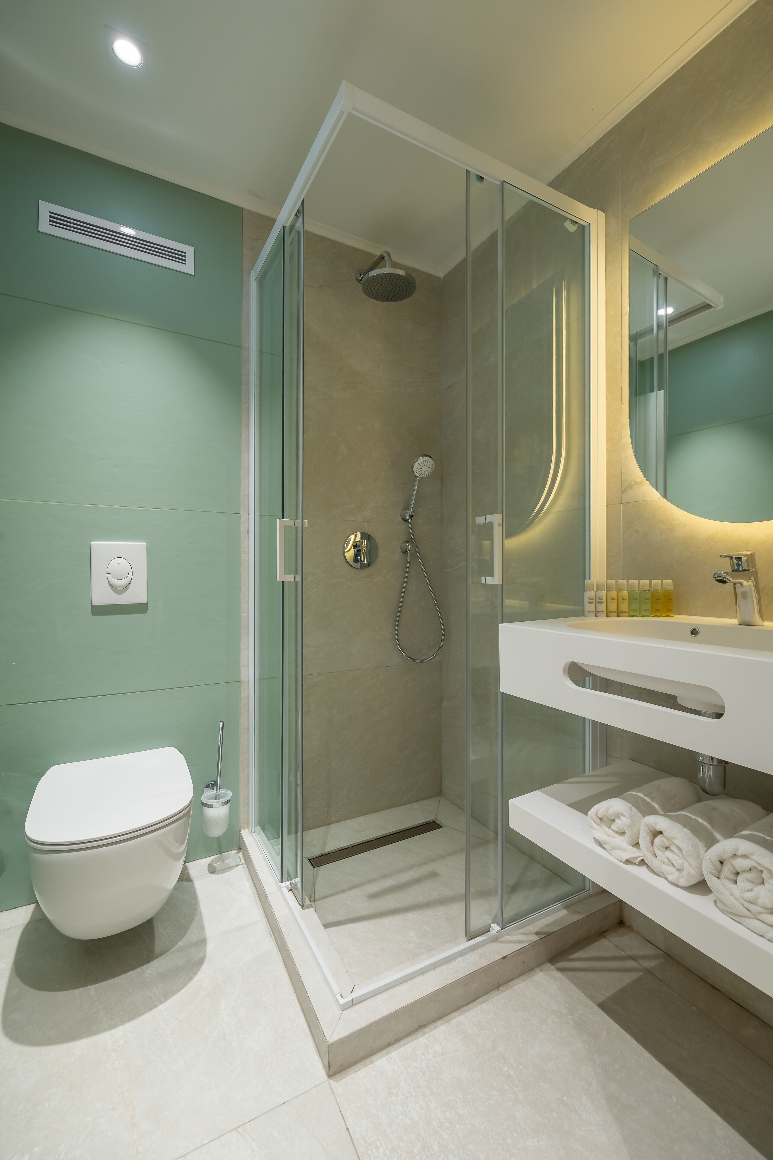 Un baño moderno con cabina de ducha de vidrio, un lavamanos blanco y un inodoro.
