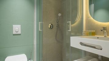 Un baño moderno con cabina de ducha de vidrio, un lavamanos blanco y un inodoro.