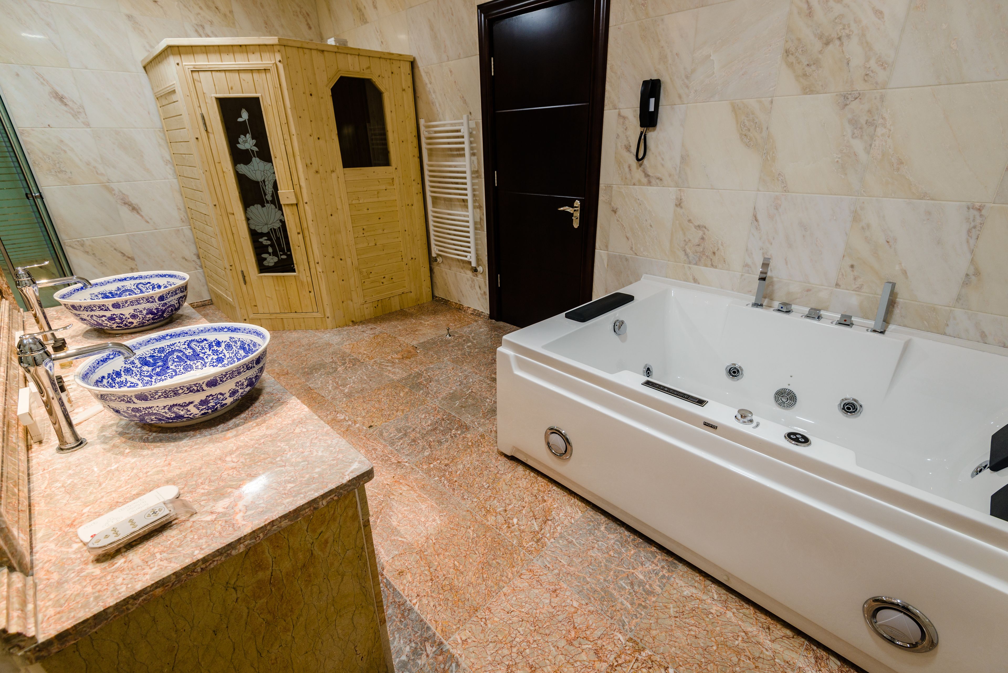 Une salle de bain avec une grande baignoire, deux bols décoratifs, un meuble en bois et un porte-serviettes.