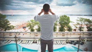 A man standing by a pool with a view of the beach and ocean. - Hotel Bavaria Blu (Constanta)