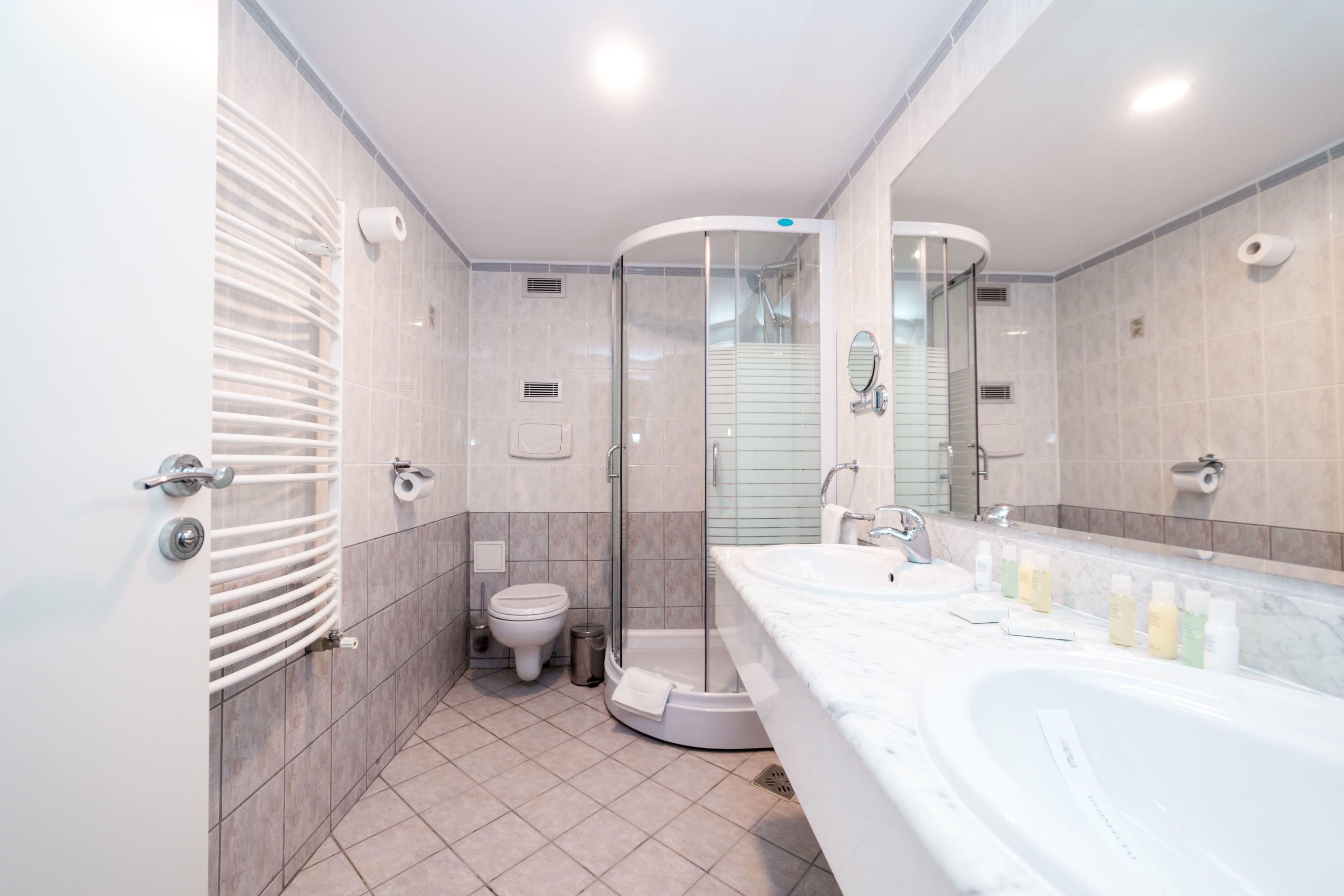 A modern bathroom with a glass-enclosed shower, a large bathtub, and a vanity with multiple sinks.