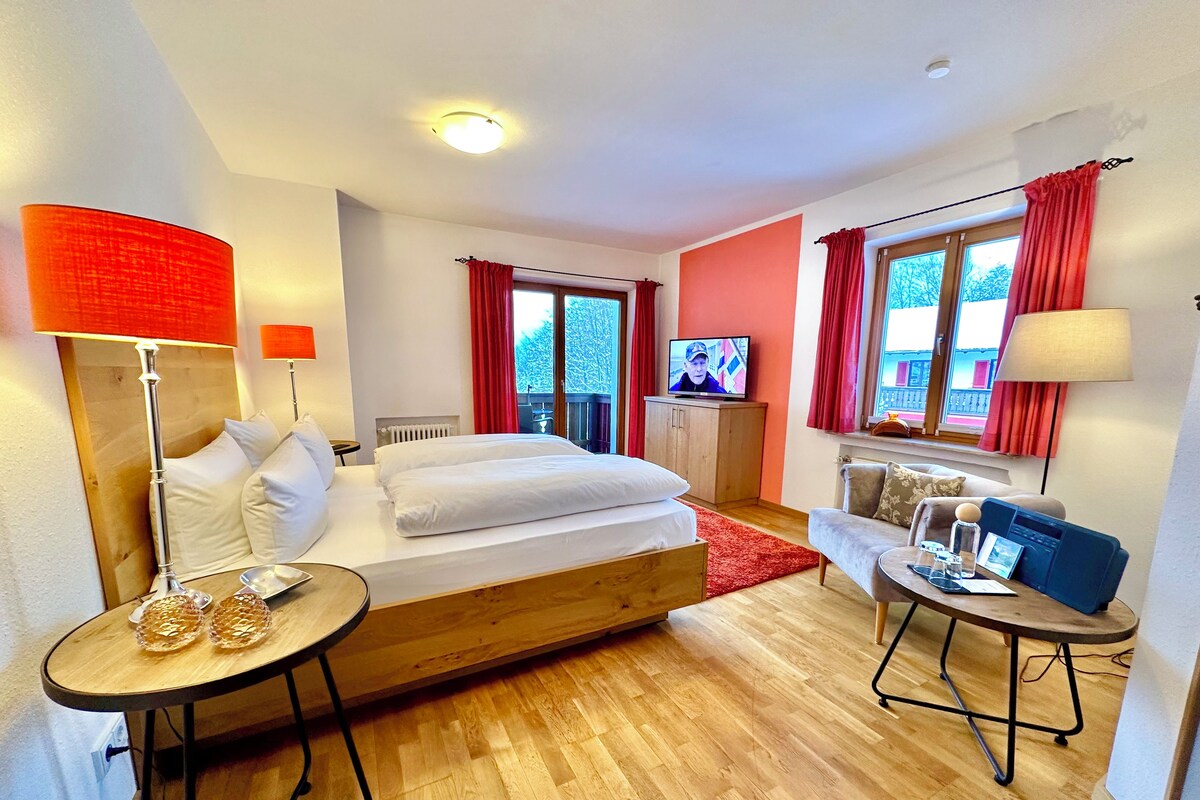 Habitación de hotel con cama, televisor, escritorio y sofá.