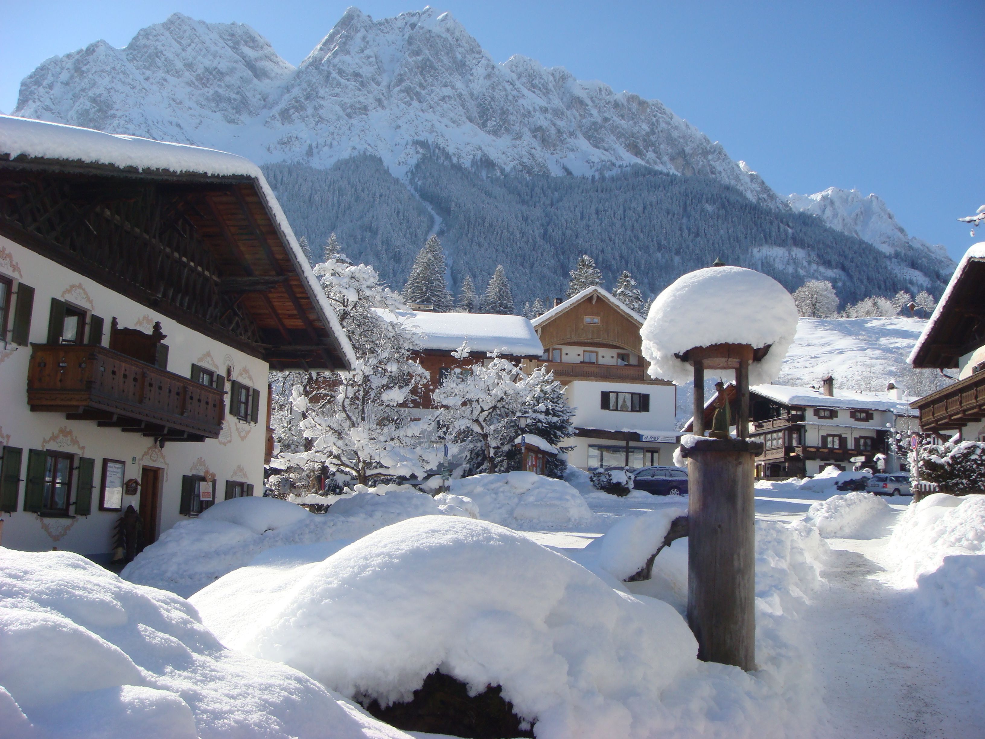 A snow-covered village with traditional wooden buildings and a mountain backdrop.